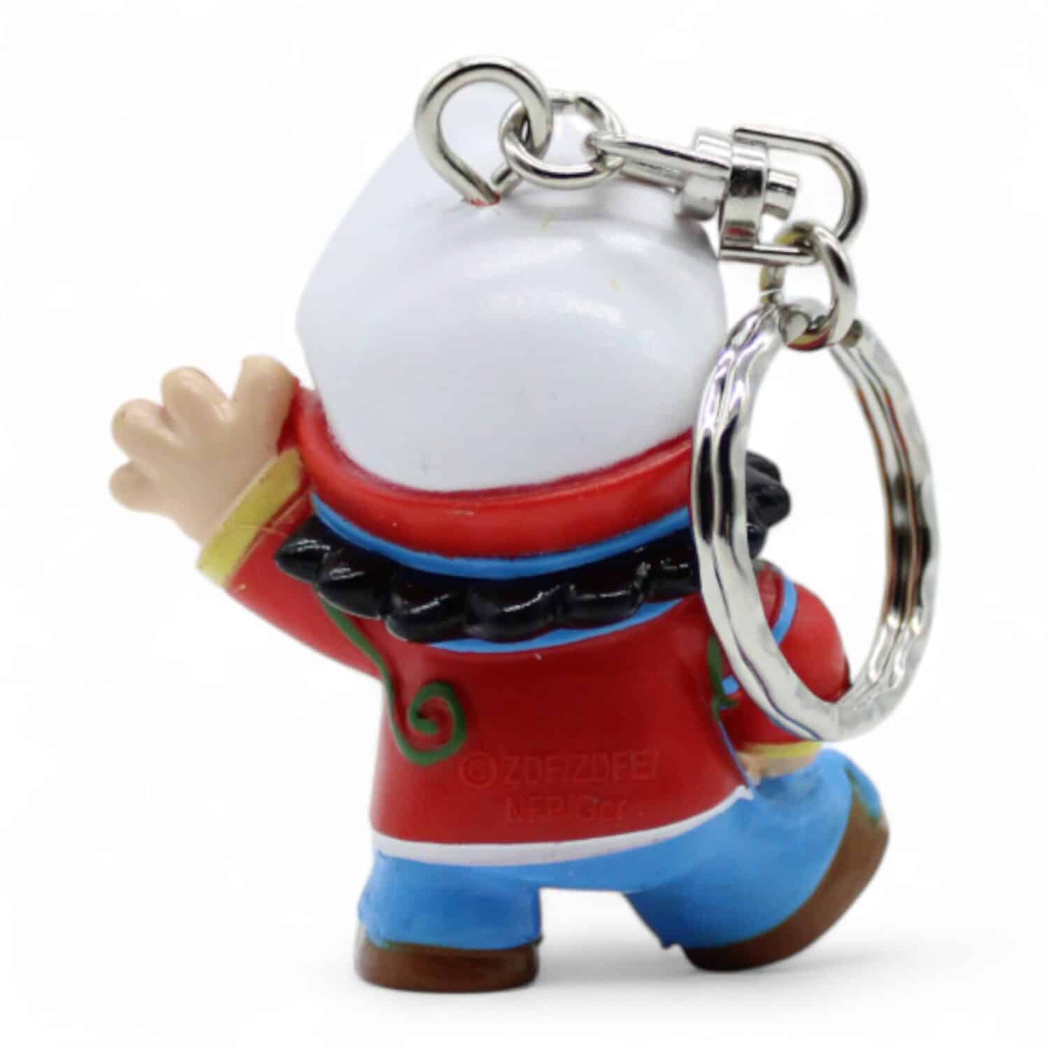 Bunter Schlüsselanhänger, fröhliche Figur mit rotem Hut und blauer Hose, hebt Hand, Schlüsselring. Rückseite