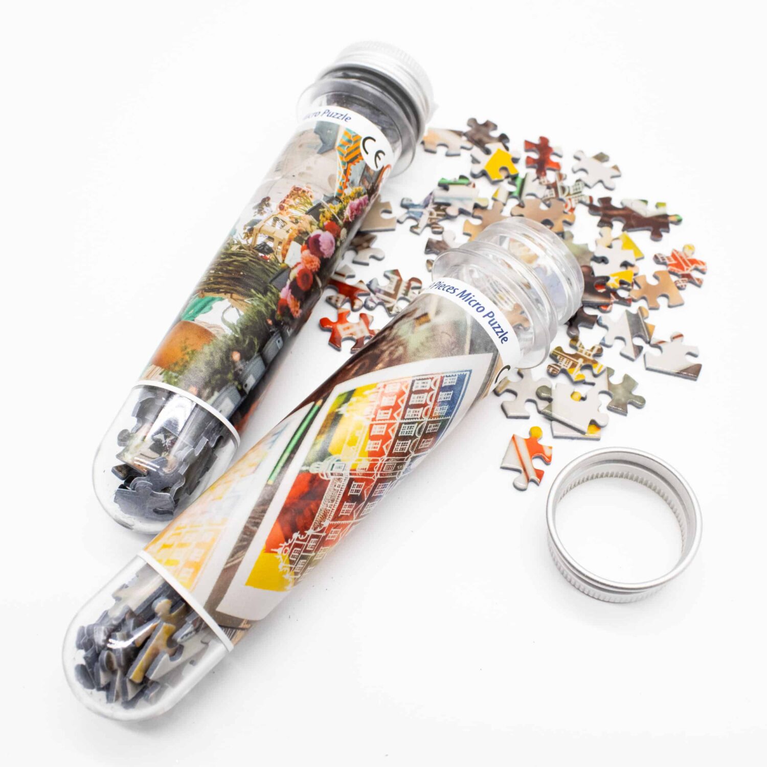 Zwei transparente Röhren mit Puzzleteilen, bunte Motive, Teile verstreut auf der Oberfläche.
